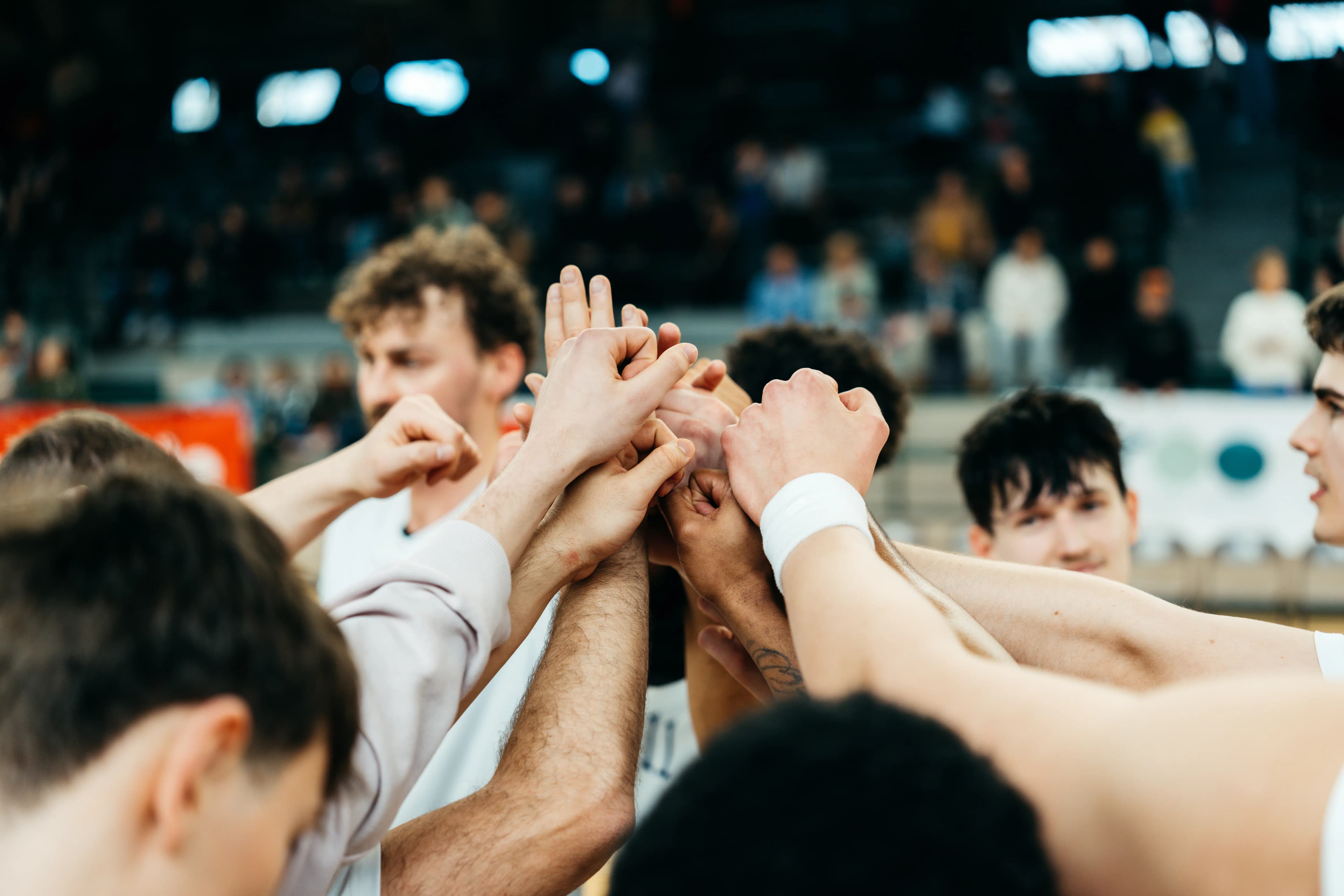 Berlin-Dreams-Team im Huddle, Hände übereinander gestapelt vor den Tribünen
